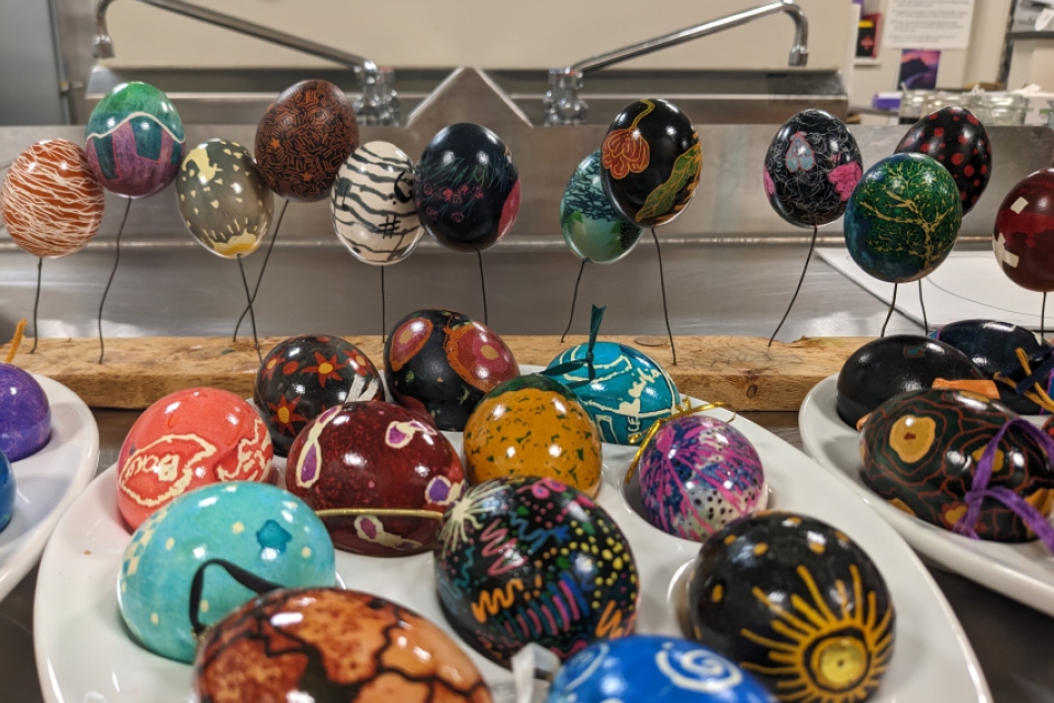 colorful painted eggs on a table and on a wire stand