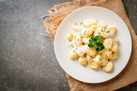a plate of gnocchi set on burlap on a gray countertop