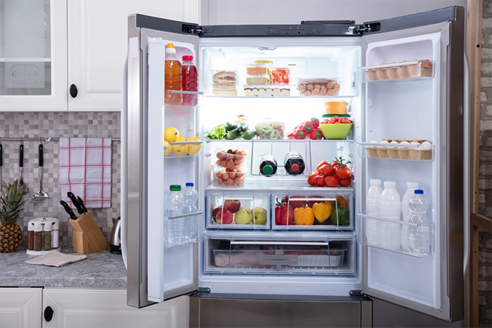 an open fridge in a kitchen, full of fruits and vegetables