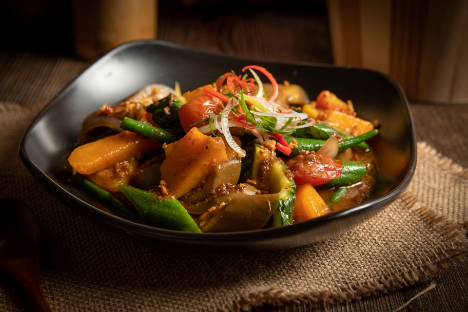 a Filipino stew of meat and mixed vegetables in a black bowl set on a piece of burlap