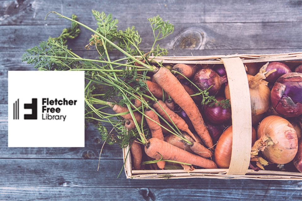 a basket of vegetables on a wooden table with the fletcher free library logo beside it