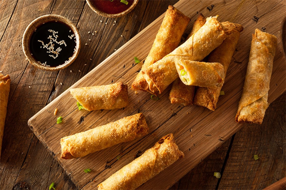 a wooden cutting board with several egg rolls