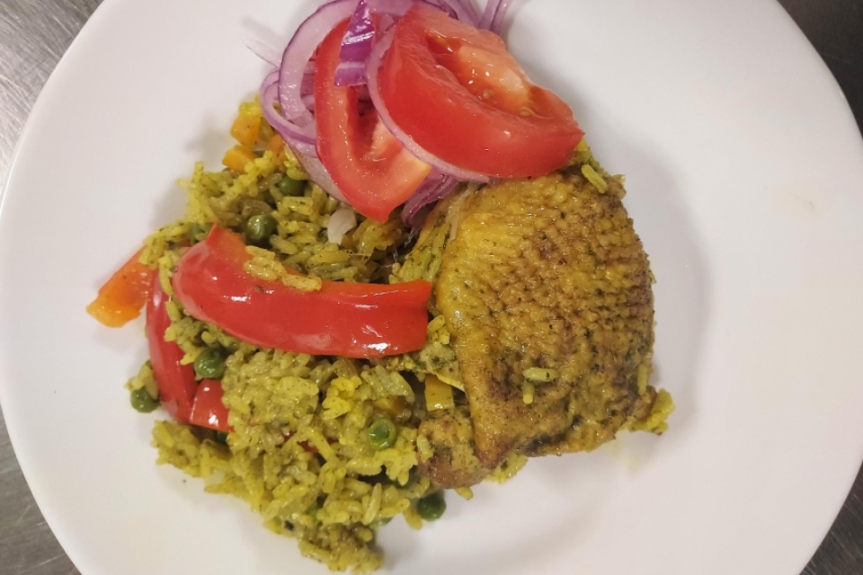 a white plate with chicken, rice, and a tomato and onion salad