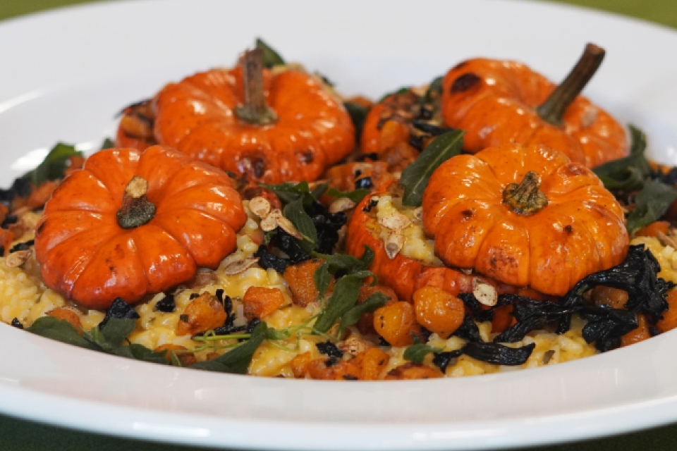 a close up of a plate. 4 pumpkins are overflowing with squash, risotto, mushrooms, and sage