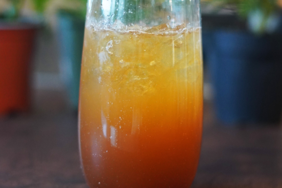 A dark and stormy in a tall clear glass, with a lime wedge on the rim. 