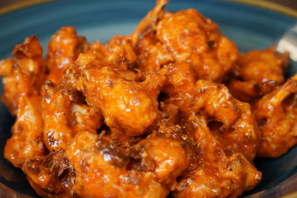 A close up shot of some orange, sauce covered and fried cauliflower florets! 