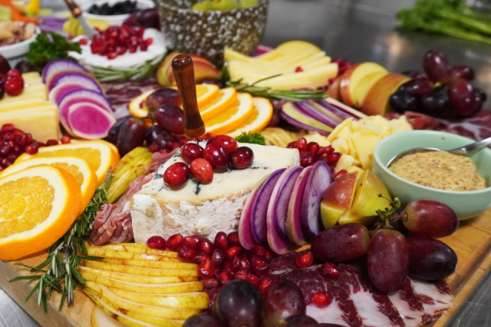 a board full of cheese, veggies, fruits, and spreads