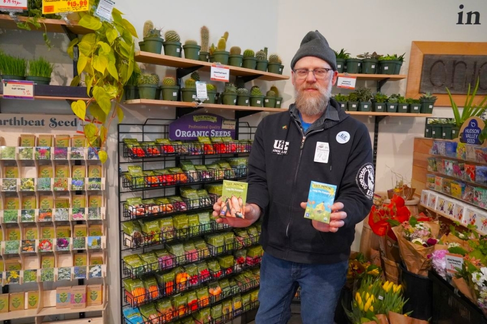 a man holds seed packets in a grocery store