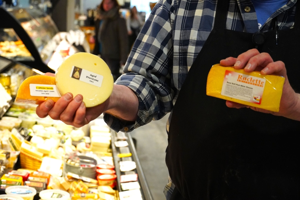 a man holds up 3 cheeses