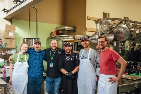 6 people standing with arms around one another and smiling in Feeding Chittenden kitchen space. 