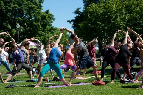 Small group of people doing yoga outside in park on a sunny day