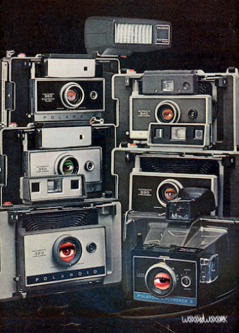 Six black and silver Polaroid accordion cameras from the 1970's to the 1980's are stacked in two columns on a black background. There is an eye visible in each lens.