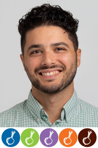 A photo of a smiling person from the shoulders up. The person is wearing a light green checkered button down shirt. They are in front of a white background.