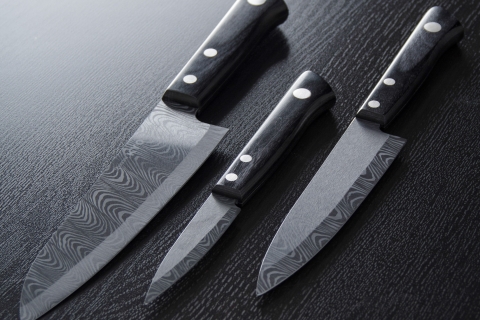 three knives of various sizes on a gray background
