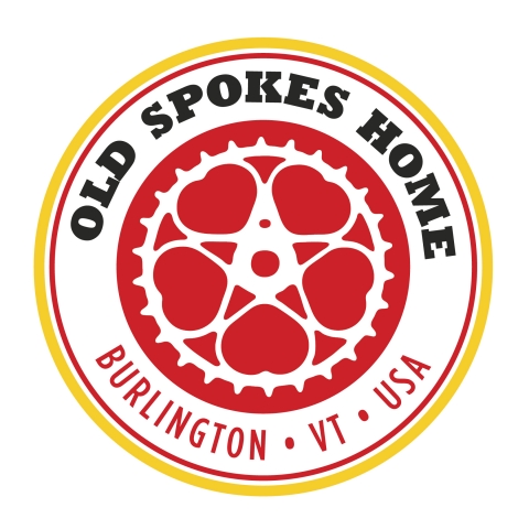 A red circle with five white interlacing gears on it. The gears form five little hearts. Around the circle are the words "Old Spokes Home, Burlington, VT, USA." There is a yellow circle around the words.