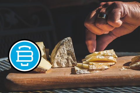 a hand reaches for a piece of cheese from a selection on a board. the burlington beer company logo is to the left