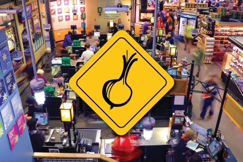 A photo of the front end of the Downtown City Market location in action. On top of the center of the photo, there is a yellow rhombus with a drawing of an onion in black at the center.