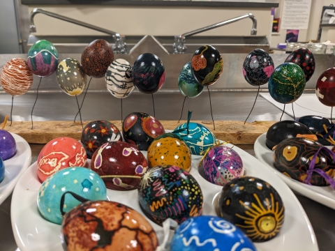 colorful painted eggs on a table and on a wire stand