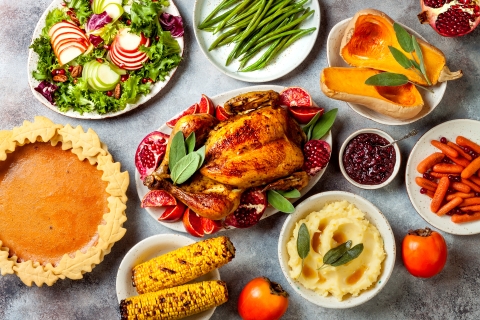 Thanksgiving dinner table with roasted whole chicken or turkey, green beans, mashed potatoes, cranberry sauce and grilled autumn vegetables. Top view, overhead