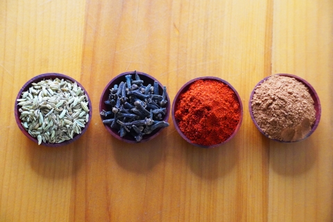 4 little wodden bowls with fennel, cloves, paprika, and ground cinnamon in them from left to right. 