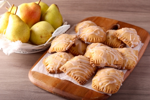 a pile of glaze hand pies next to a basket of pears