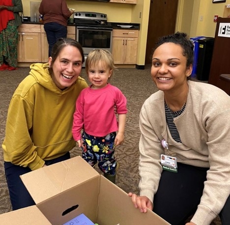 Two women smile at the camera with a toddler in between them! 