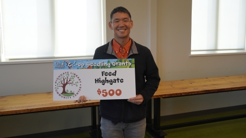 John Tashiro holds a sign that reads "Feed Highgate - $500"