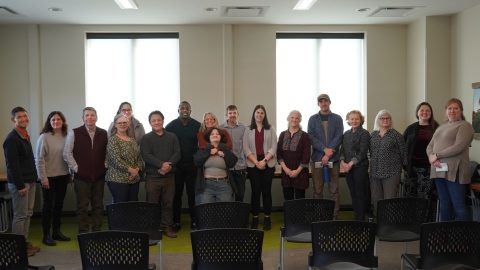 A group of people gathered in two rows in a conference room. 