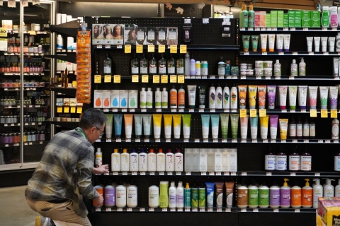 a man stocking shelves of wellness products at a grocery store