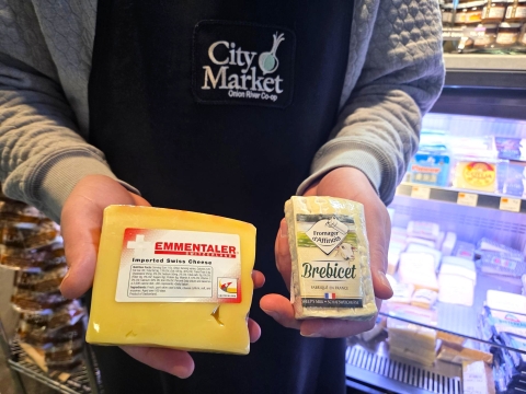  a man holds up 2 cheeses