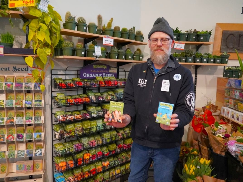 a man holds seed packets in a grocery store