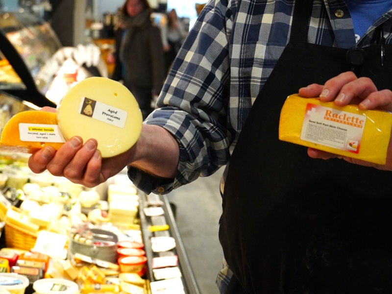 a man holds up 3 cheeses