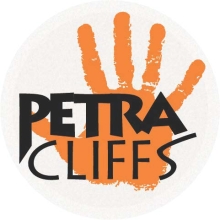An orange hand print in the background. Overlaying the handprint is "Petra Cliffs" in black